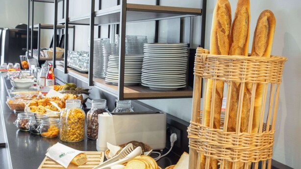 A buffet setup with various food items, including bread, pastries, and condiments.