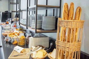 Un buffet proposant une variété de plats, notamment du pain, des pâtisseries et des condiments.