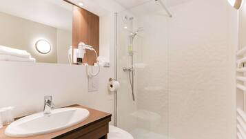 A modern bathroom with a sink, toilet, and glass shower enclosure.
