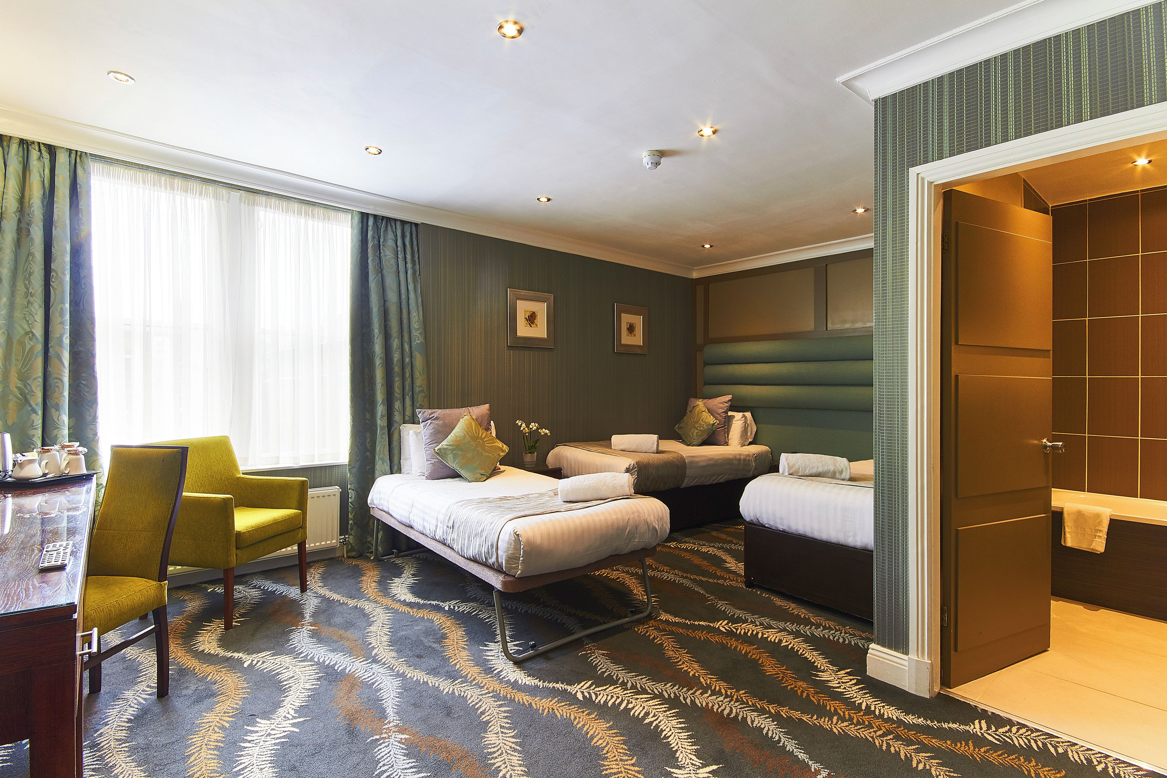 Ein Hotelzimmer mit Bett, Schreibtisch, Stuhl und Bad.
