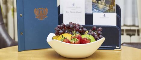 A bowl of fruit on a table with a blue folder and papers in the background.