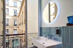 Ein Badezimmer mit einem weißen Waschbecken, einem runden Spiegel und blauen Fliesen.