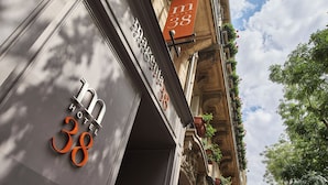 El exterior del 'Inn Hotel 38', con un letrero llamativo, arquitectura clásica y cielo despejado.