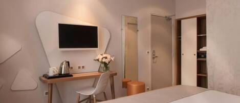 Une chambre à coucher moderne, comprenant un lit, un bureau avec une chaise, une télévision et une armoire.