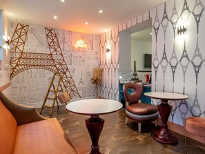 A room with a wooden ladder, two round tables, a brown leather chair, and a sofa. - ibis Styles Paris Eiffel Cambronne (Paris)