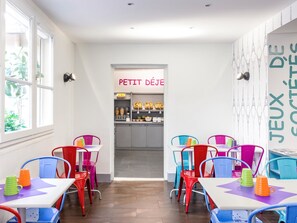 Enjoy a PETIT DEJEU breakfast at this Parisian-themed café, featuring a central counter and cozy tables with comfortable seating.