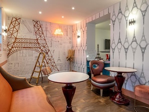 A room with a wooden ladder, a sofa, two round tables, and a chair with a circular backrest. - ibis Styles Paris Eiffel Cambronne (Paris)