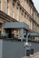 West Western Glasgow -hotellin ulkopuoli: katettu sisäänkäynti, opasteet ja harmaa seinä, jonka edessä on istutusastioita.