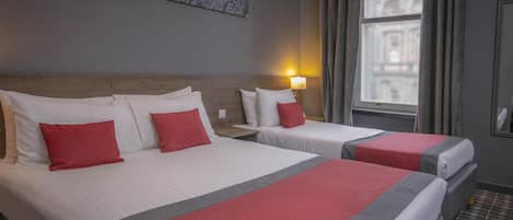 A hotel room with two beds, a nightstand, a lamp, a window with curtains, and a wall-mounted picture.