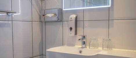 A modern bathroom with a white sink, a glass shower enclosure, and a large mirror.