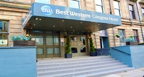 La entrada del Hotel Best Western Glasgow, con un acceso cubierto, escalones y plantas en macetas.