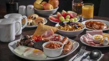 Una mesa de desayuno con diversos platos, como huevos, salchichas y tostadas.