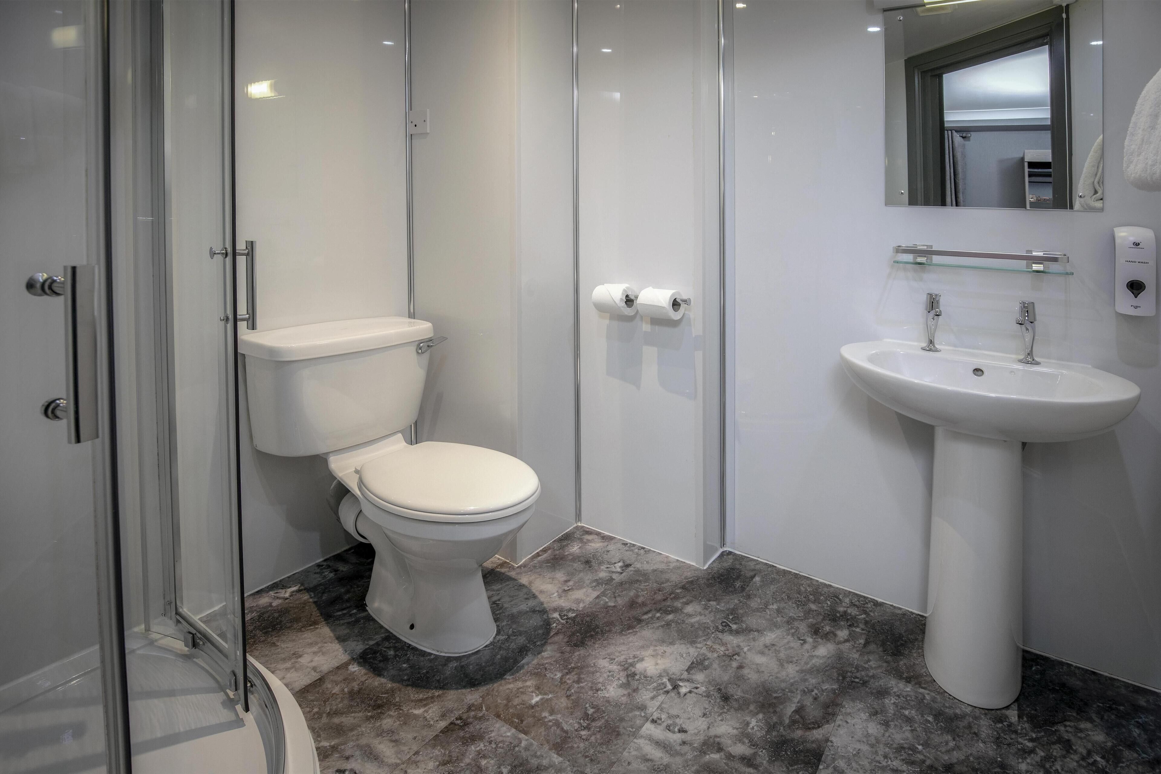 A modern bathroom with a toilet, shower, and sink.