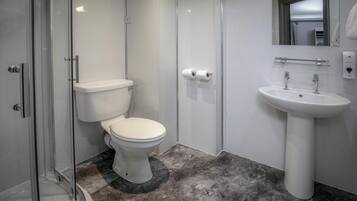 A modern bathroom with a toilet, shower, and sink.