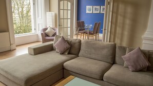 A living room with a sectional sofa, a glass coffee table, and a dining area with chairs and a table. - Dreamhouse Apartments Glasgow West End (Glasgow)