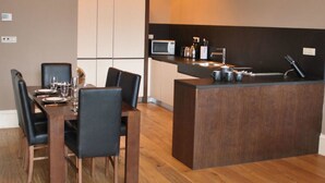 A compact kitchen with a dining area, featuring a wooden table and chairs, a built-in microwave, and a sink. - Dreamhouse Apartments Glasgow West End (Glasgow)