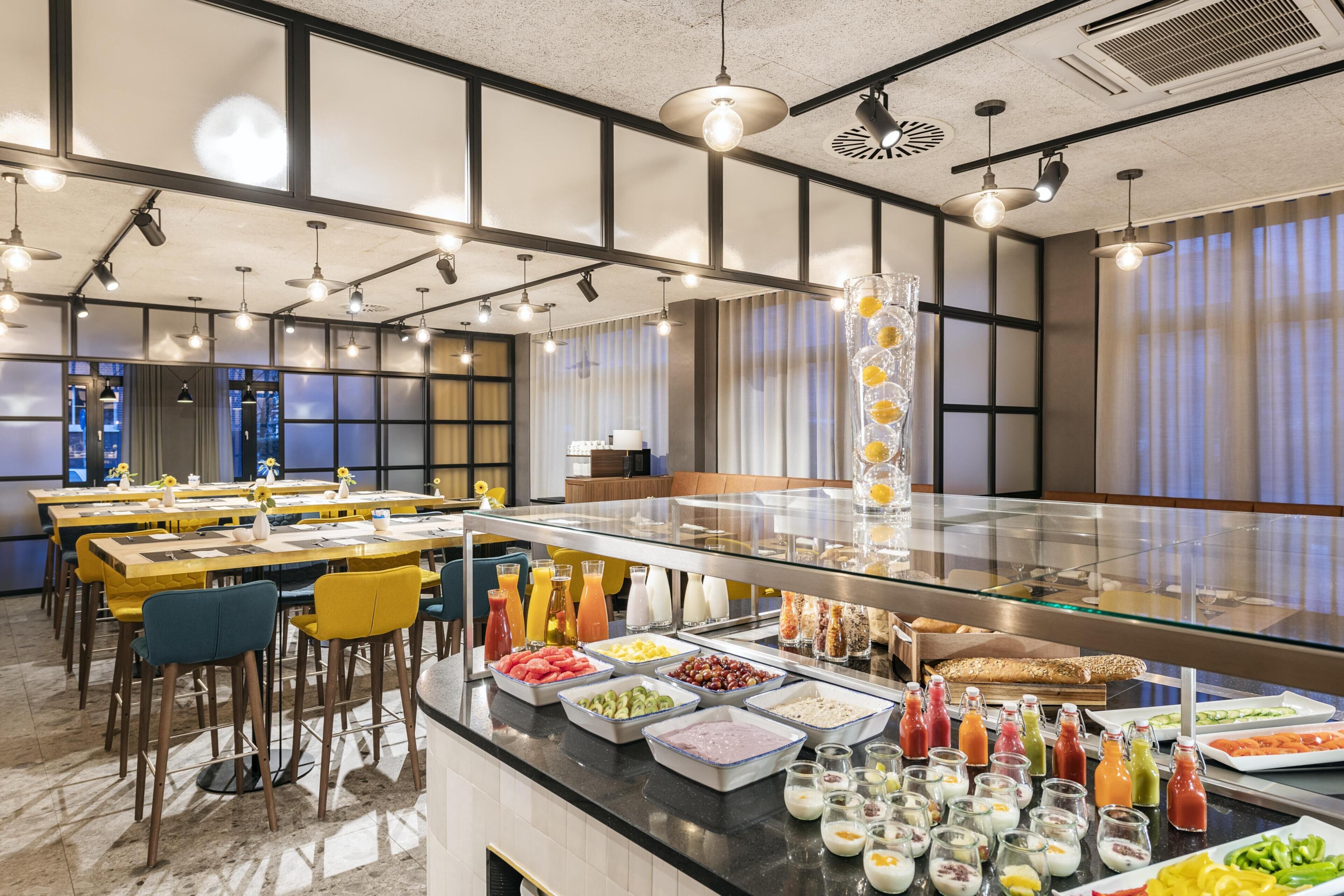 A buffet area with various food options and a seating area with yellow chairs.