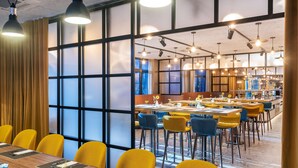 Un salón de conferencias con una larga mesa, sillas amarillas y un jarrón con girasoles.