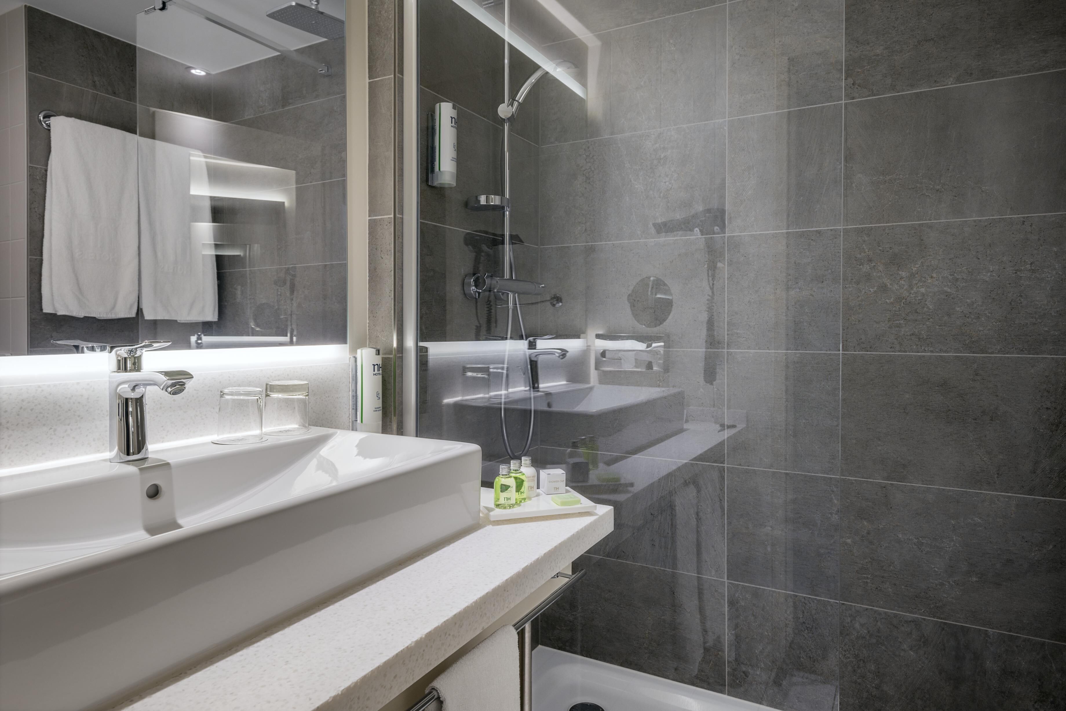 Un baño moderno con un lavamanos grande, un espejo y zona de ducha.