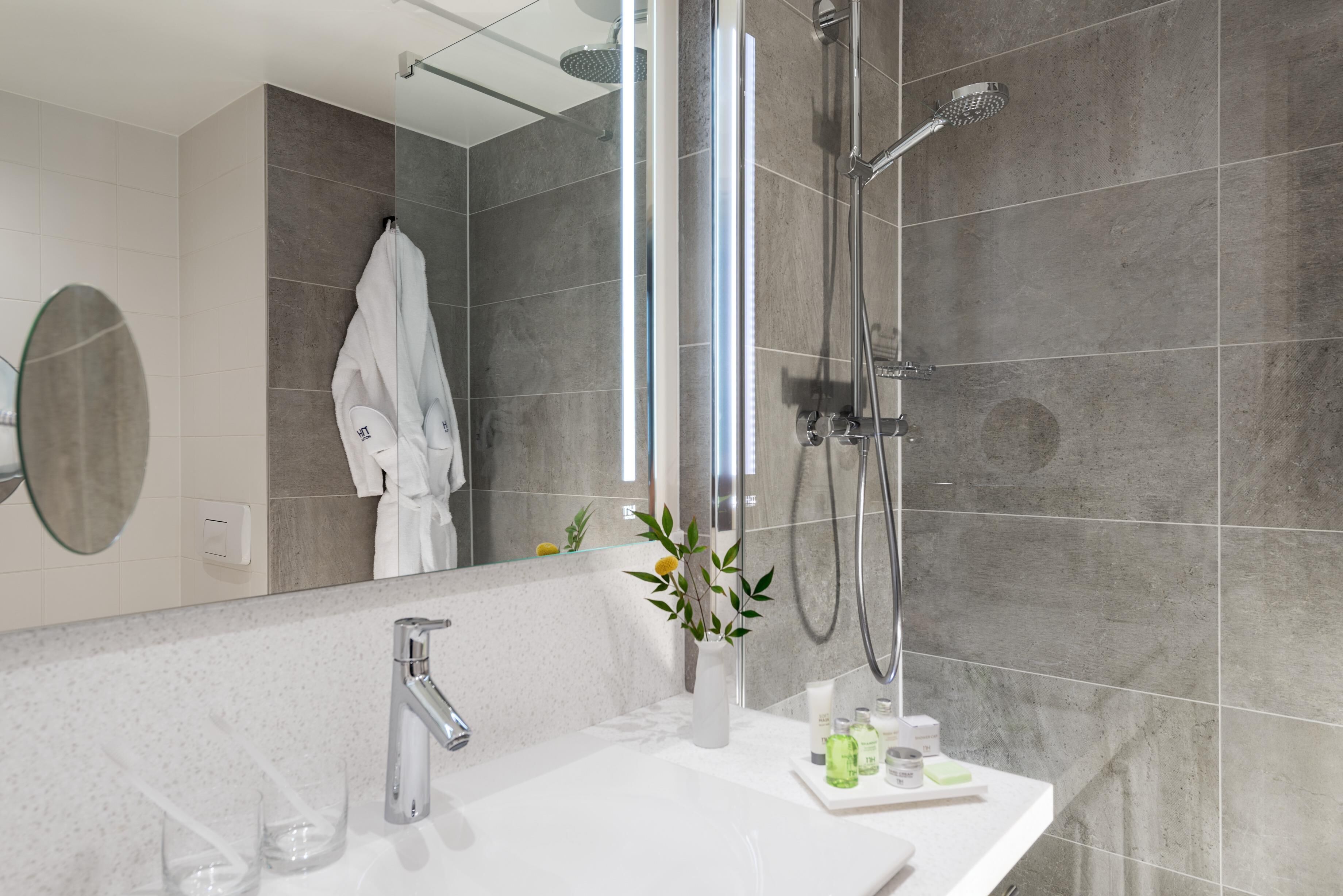 A modern bathroom with a shower, a sink, and a mirror.