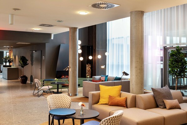 A spacious lobby with a sofa, chairs, a coffee table, and a decorative plant. - NH Köln Altstadt (Cologne)