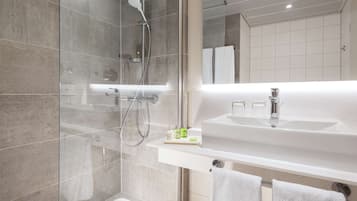 A modern bathroom with a glass-enclosed shower, a large sink, and a mirror.