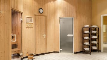 A wooden interior with a sauna, a clock, and a towel rack.