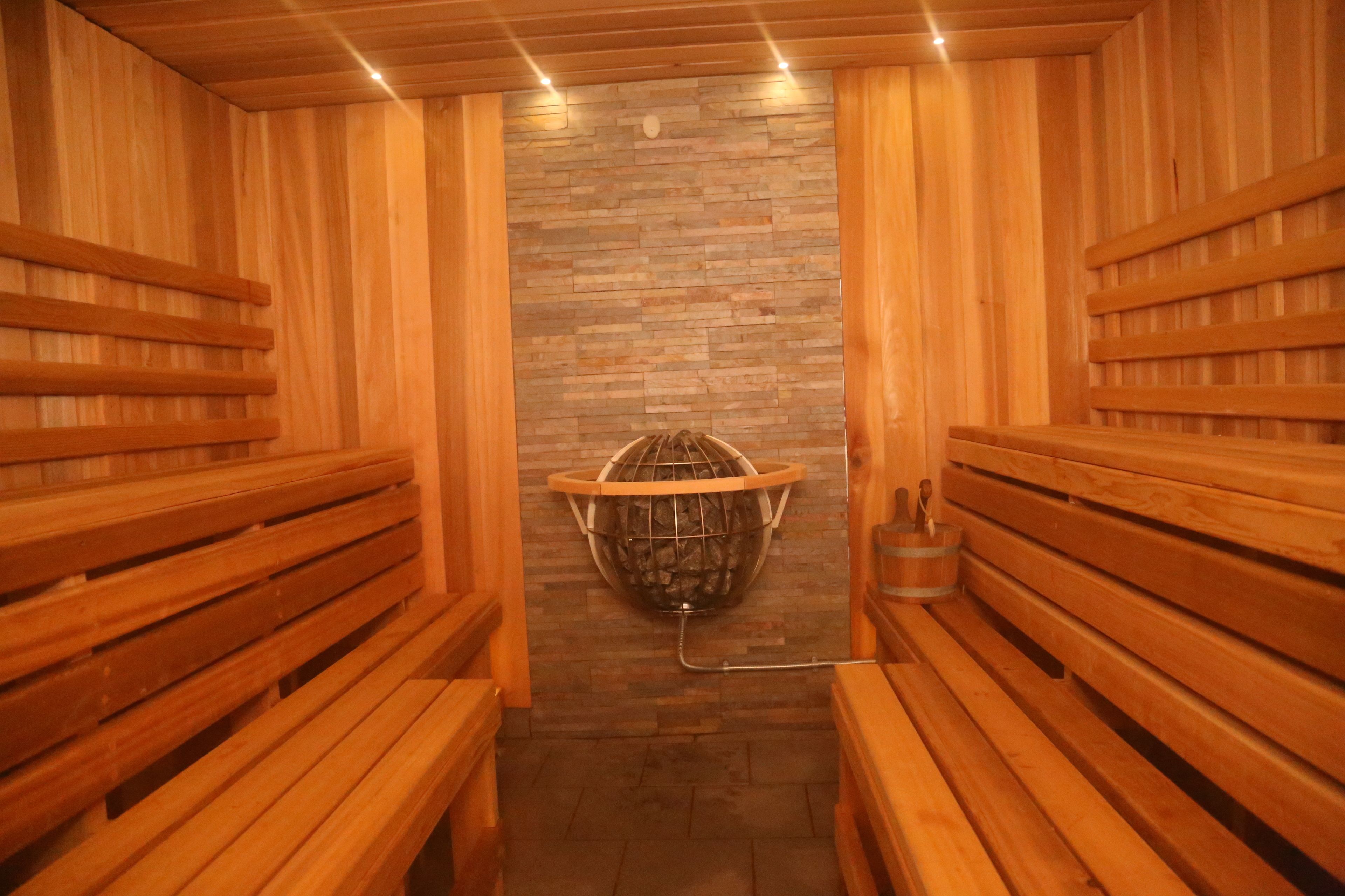 A sauna with wooden benches and a stone wall.