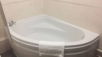 Un baño moderno con una bañera independiente, una toalla colgada al costado y paredes de azulejos.