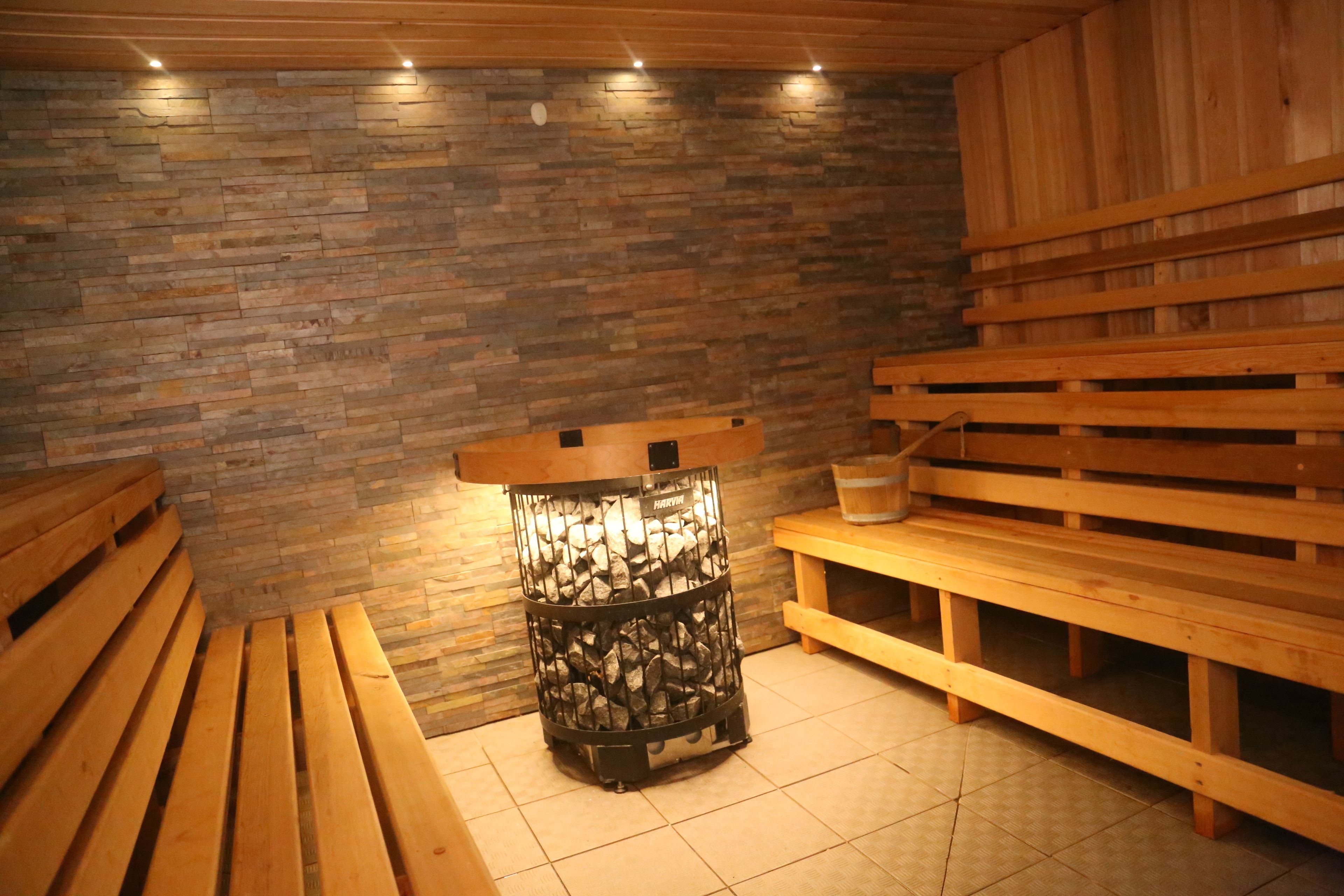Een sauna met houten banken en een stenen muur.