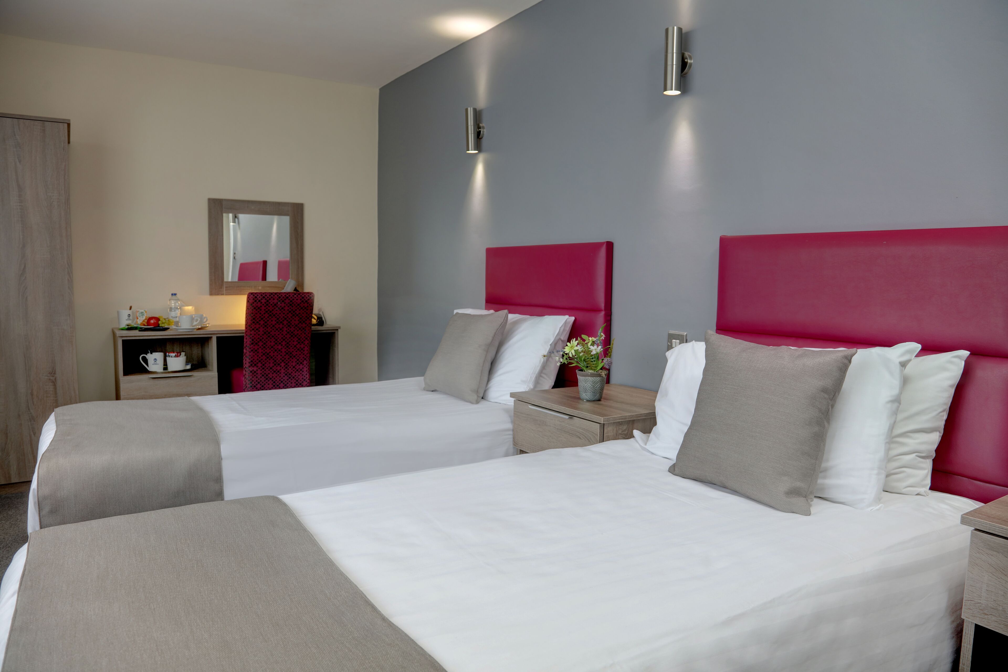Een hotelkamer met twee bedden, een bureau, een stoel en een spiegel.