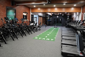 Une salle de sport équipée de tapis de course, de vélos d’appartement et de matériel de musculation.