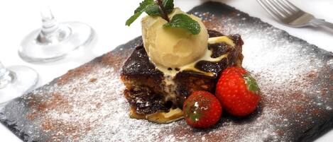 Un dessert composé de glace, de fraises et de menthe, servi sur une assiette en ardoise.