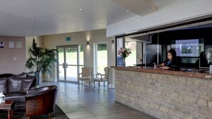 Un área de recepción con mostrador de ladrillo, sofá de cuero y sillones.