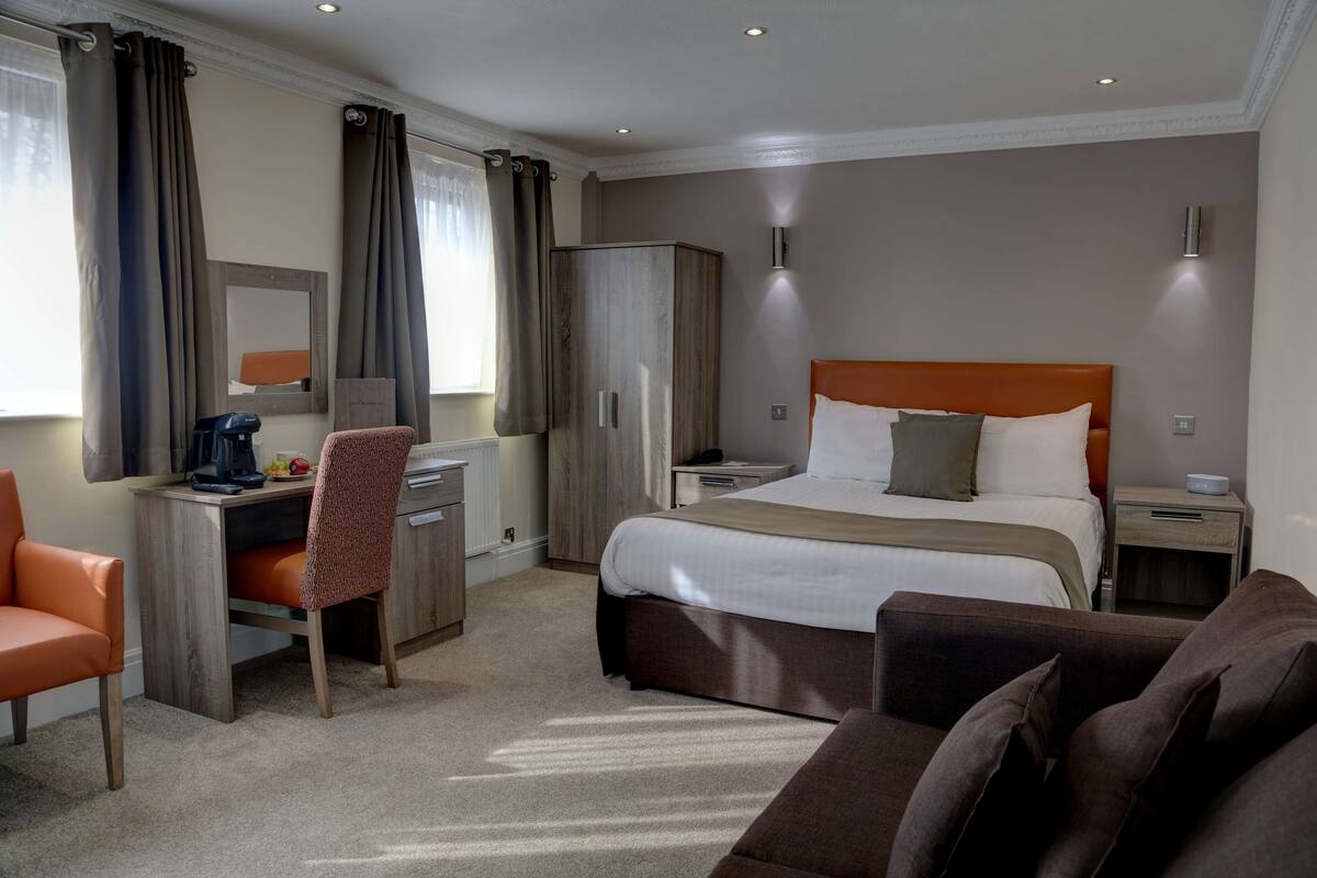Ein Hotelzimmer mit Bett, Schreibtisch, Stuhl, Kleiderschrank und einer Couch.