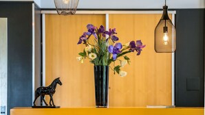 A reception desk with a vase of flowers, a horse figurine, and pendant lighting. - Best Western Adagio (Saumur)