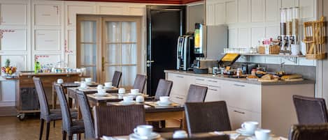 A dining area with tables set for breakfast, a coffee machine, and a counter with various items.