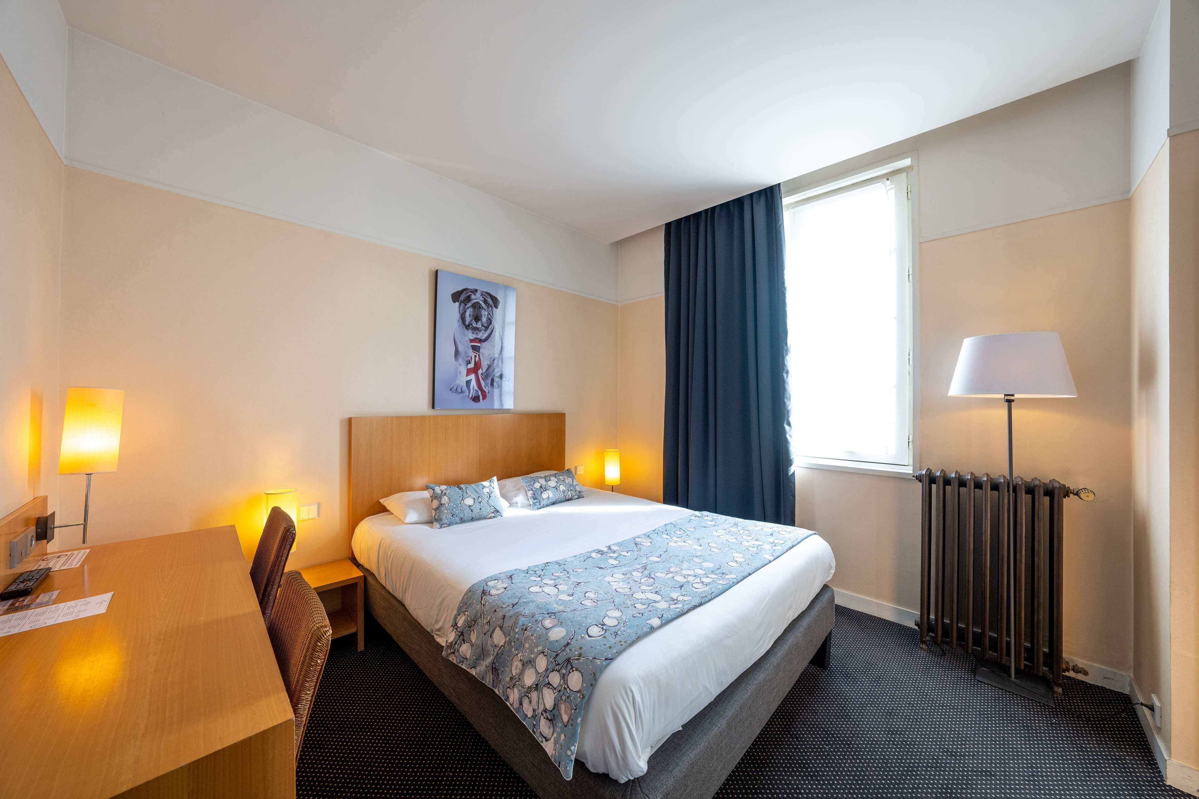 Une chambre d’hôtel avec un lit, une table de chevet, une lampe et un tableau au mur.