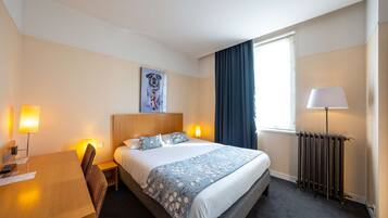 Une chambre d’hôtel avec un lit, une table de chevet, une lampe et un tableau au mur.