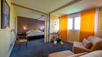 A hotel room with a bed, a desk, a chair, and a sofa.