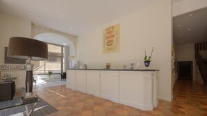 A spacious kitchen with a large island, white cabinetry, and a tiled floor. - Hotel Le Renoir (Sarlat-la-Canéda)