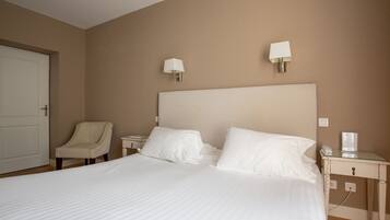 A hotel room with a large bed, two bedside tables, a chair, and two wall-mounted lamps.