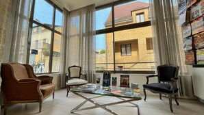 A room with large windows, a glass coffee table, and two chairs. - Hotel Le Renoir (Sarlat-la-Canéda)