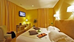 A hotel room with a bed, a desk, a chair, and a television on the wall. - Hotel Le Renoir (Sarlat-la-Canéda)