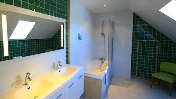 Une salle de bain moderne avec un grand miroir, deux lavabos, une baignoire et une douche.