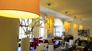 A restaurant with red chairs, white tablecloths, and a vase with flowers. - Hotel Le Renoir (Sarlat-la-Canéda)
