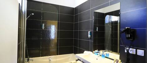 Un baño moderno con una bañera, un espejo grande y un tocador con artículos de aseo.
