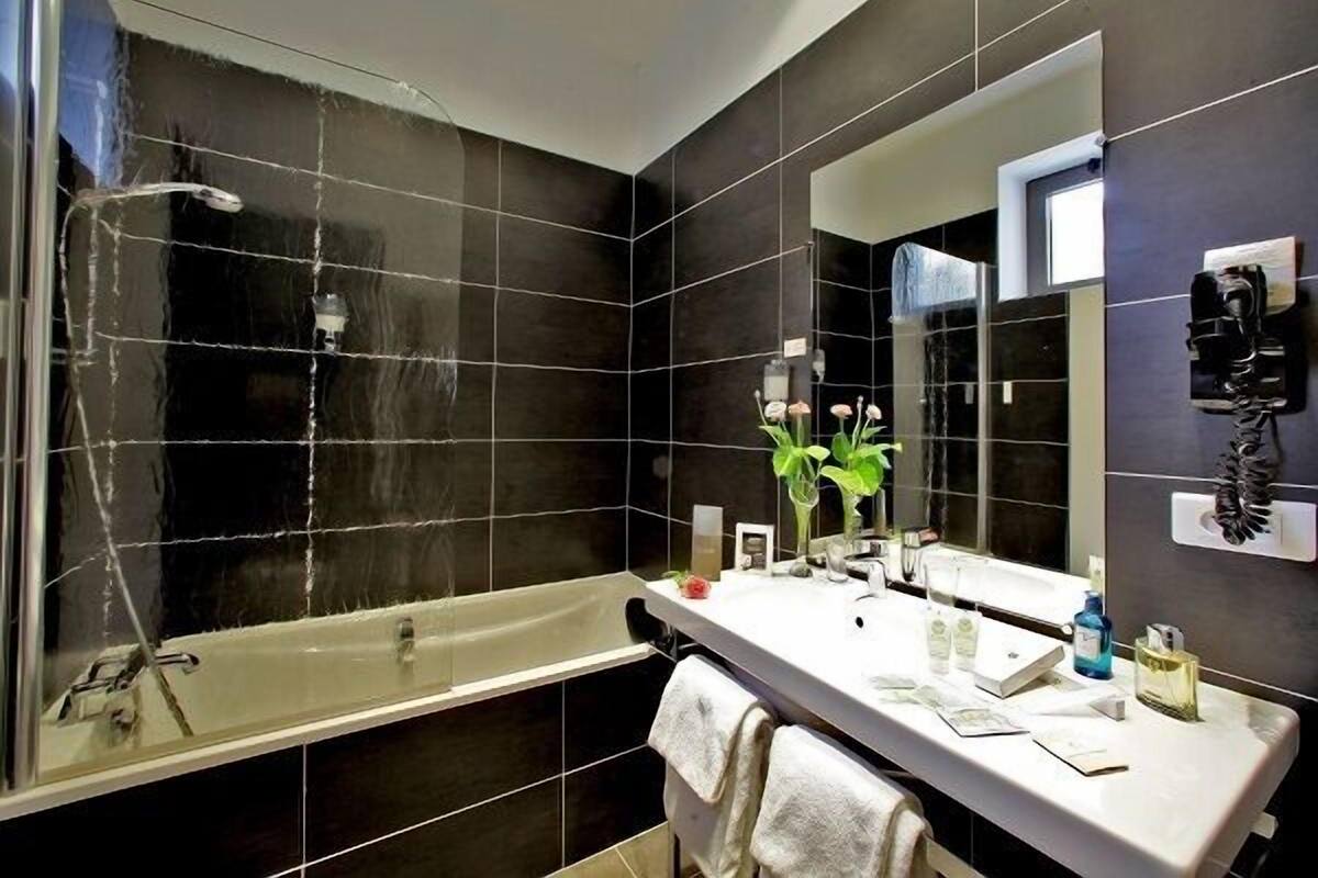 Een moderne badkamer met een badkuip, een grote spiegel en een wastafel met toiletartikelen.
