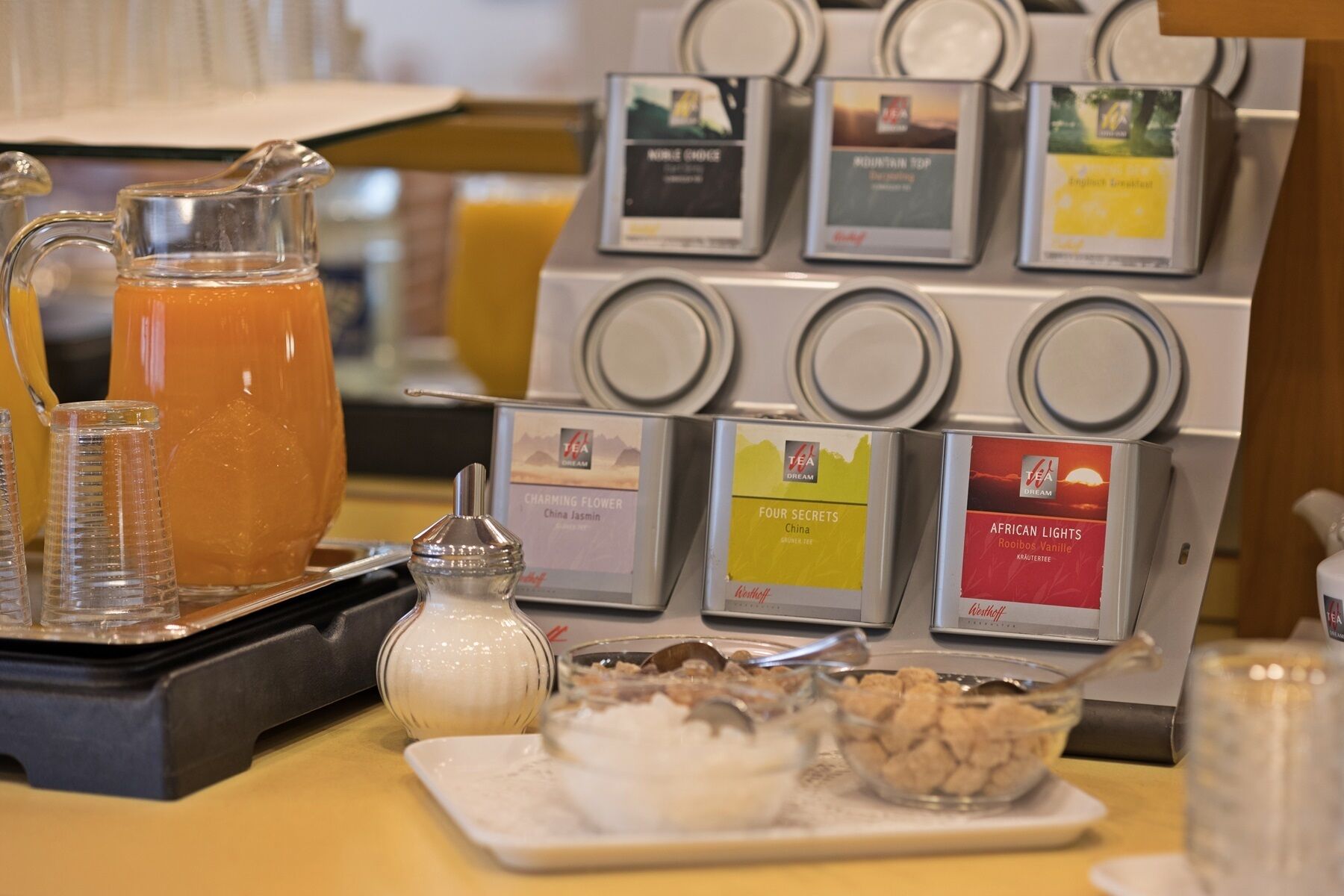 Eine Tee-Station mit verschiedenen Teebeuteln und einem Krug Orangensaft.