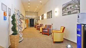 En hotellobby med en lång korridor, en sittgrupp med stolar, en vattenautomat och inramade konstverk på väggarna.